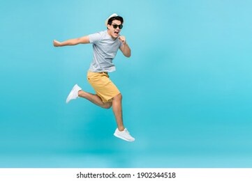 energetic happy young asian man jumping studio shot isolated in light blue background