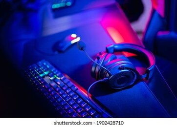 professional gamers room with headphones microphone for cyber esports and video games on neon background of gaming monitor.