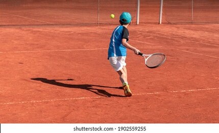 child on tennis court. boy tennis player learning to hit forehand . physical activity and sports education of children. tennis training at school or club. background, copy space