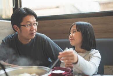 asian father and daughter eating lunch in the restaurant