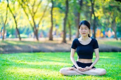 asian woman wearing a black dress  meditation in the park
