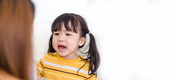 angry asian kid.little asian girl looking at her mother and fighting with her mom.furious hungry toddler kid got upset and sad.stubborn child bad attitude.depressed little girl complaining with mom.