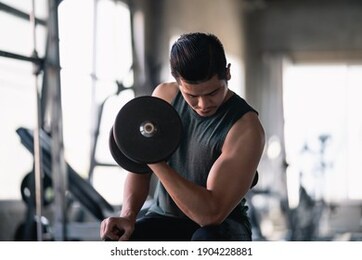 close up of man using dumbbell exercise at gym, sport concept