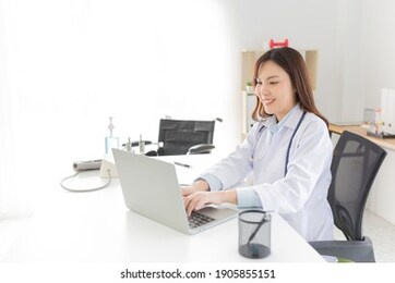 asian female doctor typing report with laptop, she feeling happy and relax in hospital