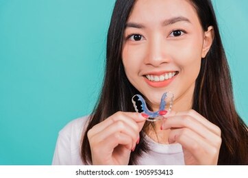 teeth retaining tools after removable braces, portrait young asian beautiful woman smiling holding silicone orthodontic retainers for teeth, orthodontics dental healthy care concept