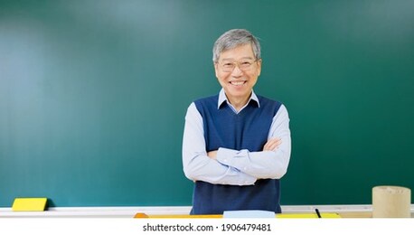 asian senior male professor arm crossed and smile at you in front of blackboard in the college classroom