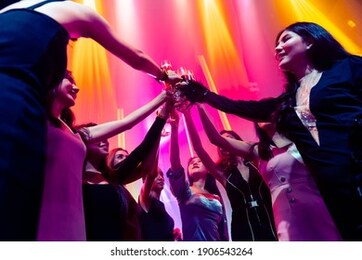 young people celebrating a party, drink and dance . group of friend toasting drinks while having fun at the disco club at night . friendship and nightlife concept .