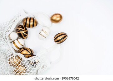 gold, black, white easter eggs in a string bag on a white background. geometry. the minimal concept of easter. top view. an easter card with a copy of the place for the text.