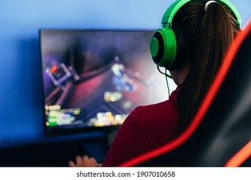 a young girl playing a computer game on professional armchair against monitor in green headphones, live stream, esports.