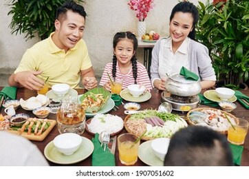 happy parents and childen eating dinner and talking at family celebration
