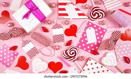 happy valentine's day gift wrap theme on trend overhead with pink, red and white gifts, cards, tags and candy on textured pink background. top view blog hero header creative composition flat lay.