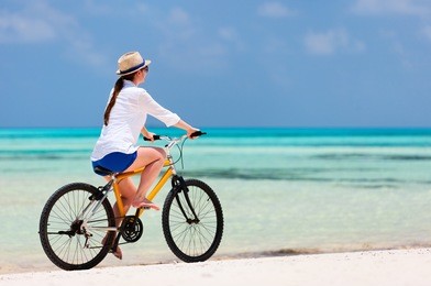 young woman on summer vacation biking at tropical beach