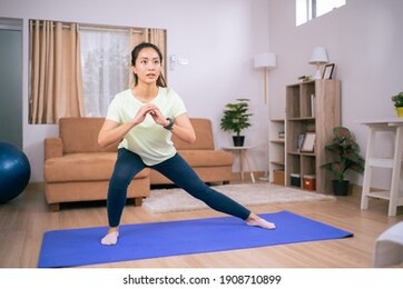 beautiful asian woman, she exercises at home, she does squats.