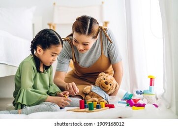 portrait of enjoy happy love asian family mother and little asian girl smiling playing with toy build wooden blocks board game in moments good time at home
