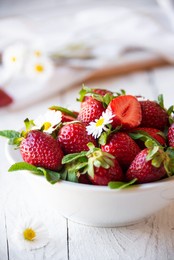 fresh strawberries in white bowl with leaves and flowers
