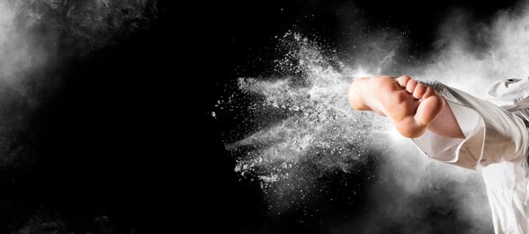 woman in kimono practicing taekwondo on black background. sports banner. horizontal copy space background 