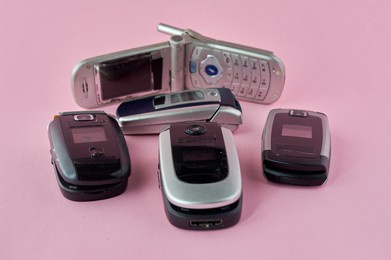 broken mobile phones, recycling technology, early 2000s on pink background and copy space,.