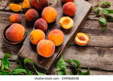 peaches with leaves on a wooden board with peach in halves. flat lay composition with ripe juicy peaches. harvest of peaches for food or juice. top view fresh organic fruit food with copy space