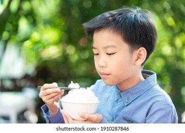 close up young asian boy using chop stick to eat rice