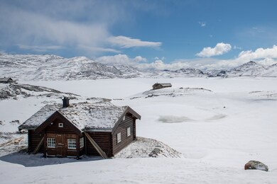 the snow-capped house is located on a hilltop and is covered with white flowery snow all the time, the sky is blue and there are white clouds