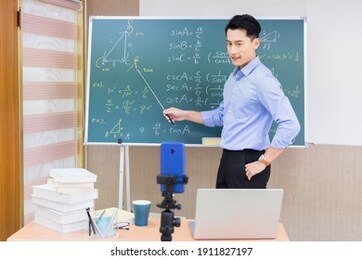 asian senior high school male teacher teach math online through mobile phone in classroom