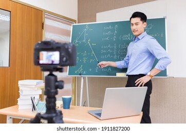 asian senior high school male teacher teach math online through camera in classroom
