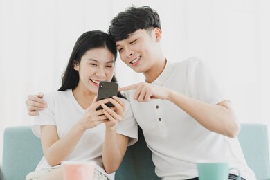 young couple looking at the phone together with happy expression