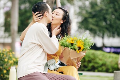 beautiful young chinese couple in love kissing on bench in park when having romantic date