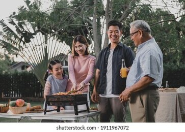 asian family having a barbecue party at home. cooking grilled bbq for dinner in backyard. lifestyle on summer holiday.