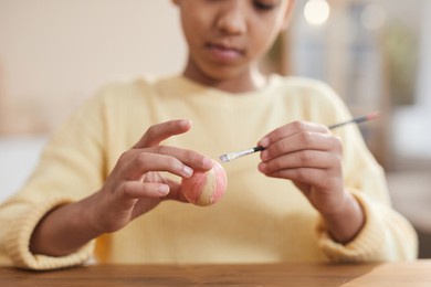 close up of young african-american girl hand painting easter eggs with pastel colors while enjoying diy decorating at home, copy space