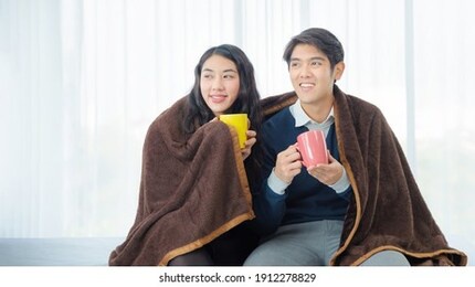happy young asian couple drinking coffee at home. loving couple with hot drinks. valentine's day