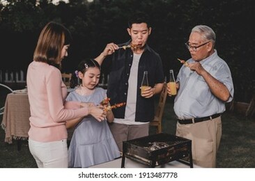 asian family having a barbecue party at home. cooking grilled bbq for dinner in backyard. lifestyle on summer holiday.