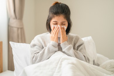 young women have symptom sick and sneezing with tissue paper in bedroom