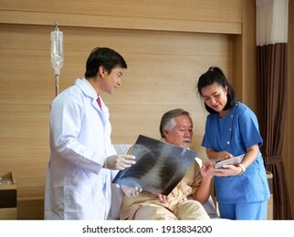 doctor and nurse talking to male senior patient  about lung x-ray film with tablet at hospital. for medicine, age, health care and senior man concept