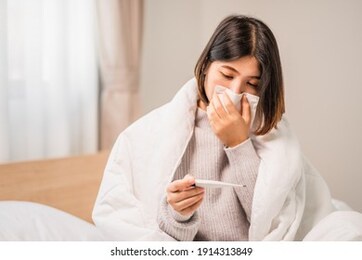 young women have symptom sick and sneezing blowing nose tissue paper with look up to digital thermometer in bedroom 