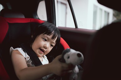 asian cute girl play puppy doll in car seat. concept for family life in car.