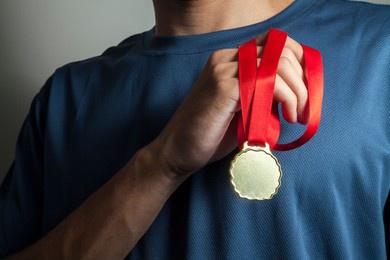 man holding gold medal with hands at chest height and with a neutral bottom.  award concept.
