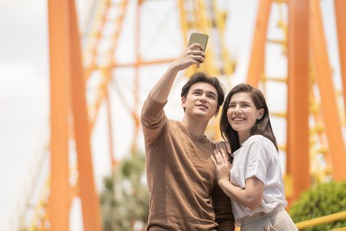 couple of man and woman using phone selfie at outdoor public amusement park. people enjoy activity of love and enjoy lifestyle of dating and traveling.