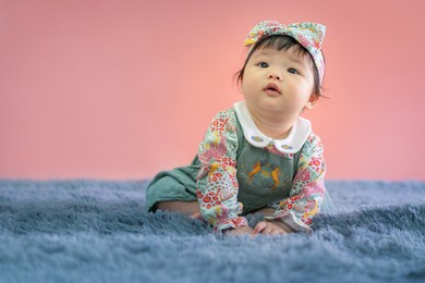 asian happy baby smiling and sitting on carpet with pink color background. cute 6 months baby start sitting with copy space use as concept of valentine, love, baby or kid department in hospital.