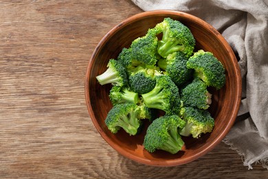 bowl of fresh broccoli florets on wooden background, top view