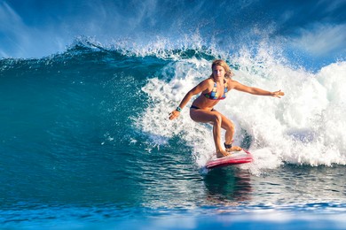 female surfer on a blue wave at sunny day