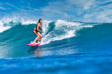 female surfer on a blue wave at sunny day
