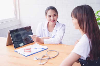 happy smiling asian female dentist doctor examining teeth diagnosing patient using tablet x-ray technology, dental hygiene care professional expert orthodontist specialist, hospital meeting office