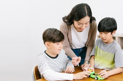 group of elementary happy kids and asian female teacher making electronic toys with colorful in science lesson class. education, elementary school, learning, science workshop concept. copy space