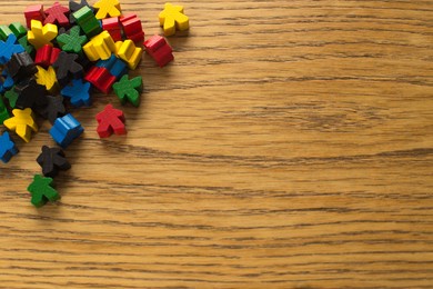 colorful meeple on wooden background. board game concept. diversity of people and colors. the chips are out of order on the table.