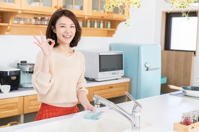 young attractive asian woman washing the dishes in a kitchen