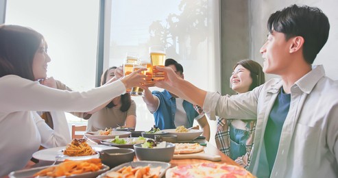 group of asian happy friends drinking and toasting beer in restaurant