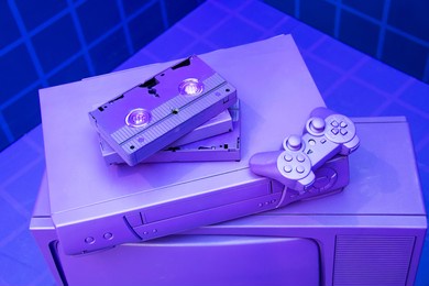 vcr for videotapes, a game joystick lie on a violet, purple vintage tv. concept for the return of the lifestyle of youth and adolescents in the 80s and 90s