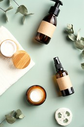 set of amber glass cosmetic bottles, jars of moisturizer cream, loofah, eucalyptus leaves on green background. spa natural organic beauty products packaging design.
