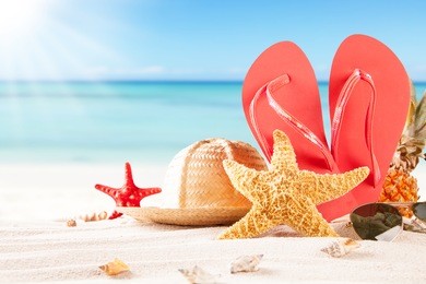 summer concept of sandy beach, straw hat, shells and starfish.